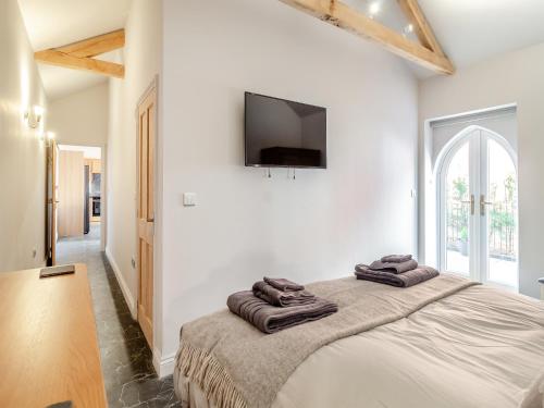 a bedroom with a large bed with a flat screen tv on the wall at Bell House Stables - Uk41789 in Melton Constable