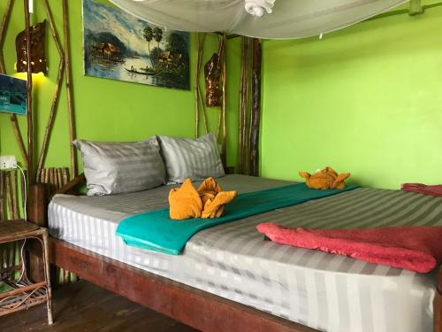 ein Bett mit zwei ausgestopften Tieren darüber in der Unterkunft Sunny Bungalow in Koh Rong Sanloem