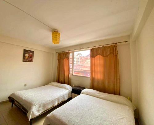two beds in a room with a window at Vila Festiva Cochabamba céntrica in Cochabamba