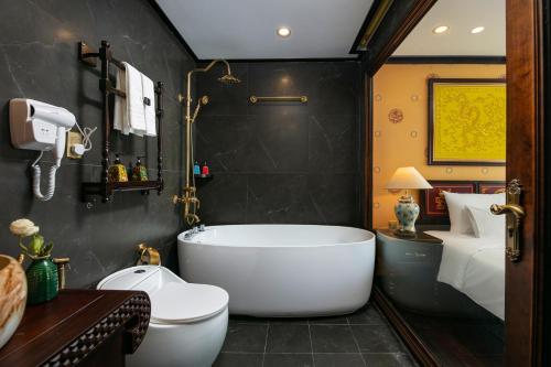 a bathroom with a bath tub and a bedroom at Nostalgia Halong Cruise in Ha Long