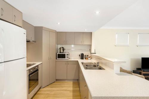 a white kitchen with a sink and a microwave at Tides at 65 Cape View Resort in Broadwater