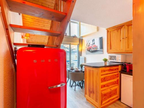 - un réfrigérateur rouge dans la cuisine avec une table dans l'établissement Appartement 5 pers à Saint-Lary avec WiFi - FR-1-296-460, à Saint-Lary-Soulan