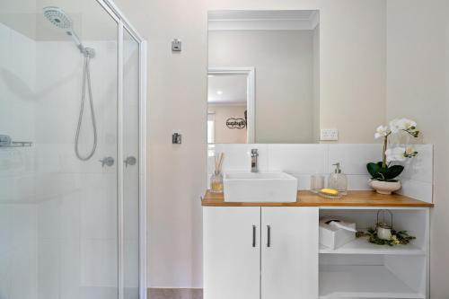 a white bathroom with a sink and a shower at Tell Tales Bed & Breakfast in Creswick