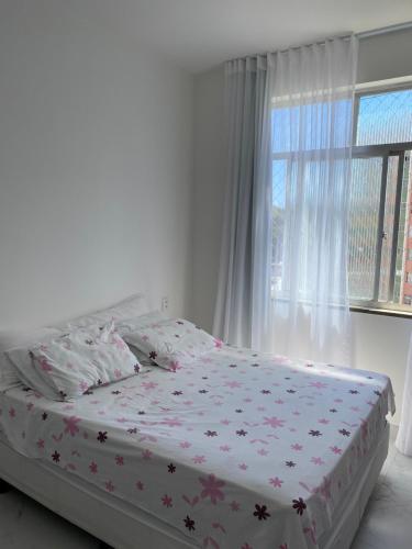 1 dormitorio con 1 cama con colcha de flores y ventana en Feriado em Salvador!, en Salvador