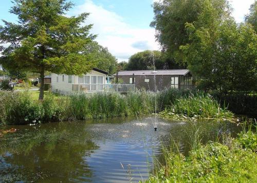 a pond in front of a house with a house at Fir Trees in Chester