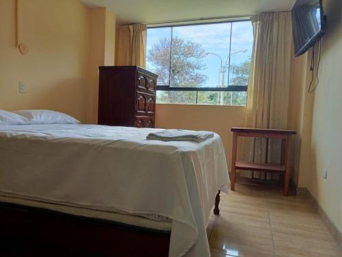 een slaapkamer met een bed, een dressoir en een raam bij ROARI HOTEL in Trujillo