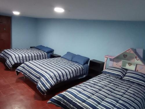 three beds in a room with blue walls at Habitación Privada (15m2) - Baño Compartido in Cajamarca