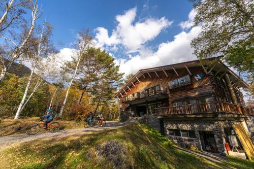 two people riding bikes in front of a log house at NORTHSTAR Loft in Matsumoto