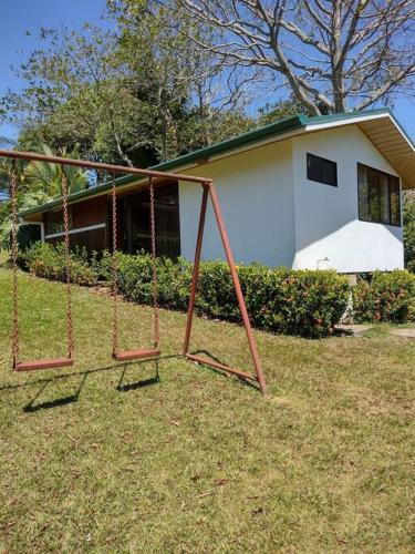 a swing set in a yard in front of a house at Eco Villas Tambor Tucanes in Tambor