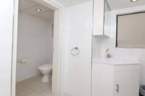 een witte badkamer met een toilet en een wastafel bij Palm Breeze - Hosted by Burleigh Letting in Gold Coast