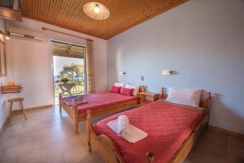 a bedroom with two beds and a table and a window at Jimmy's Sea View Studios in Tragaki
