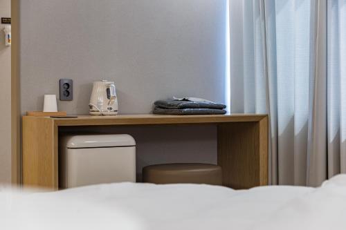 a room with a desk with a toilet and a table with a telephone at Brown Dot Hotel Cheonan Buldang in Cheonan