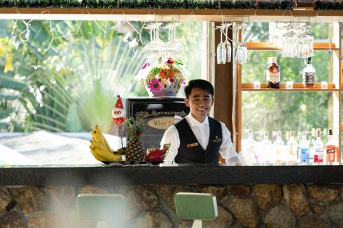 Un hombre de pie detrás de una barra en un restaurante. en Panorama Samui Residences, en Ban Bang Po