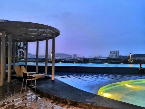 una piscina con una silla y una mesa y un edificio en Cheras Lovely Studio House with Netflix and free car park, en Cheras