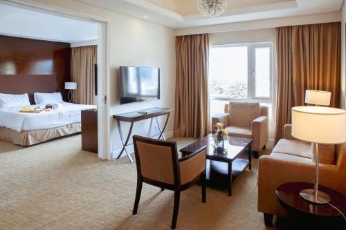 een hotelkamer met een bed en een woonkamer bij Harolds Evotel Cebu in Cebu City