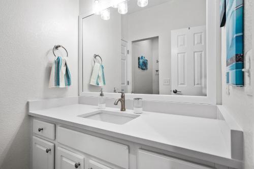 La salle de bains blanche est pourvue d'un lavabo et d'un miroir. dans l'établissement Luxury multi-family getaway w kids at Frisco, TX, à Frisco