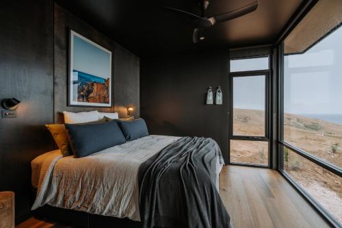 ein Schlafzimmer mit einem Bett und einem großen Fenster in der Unterkunft Wander on Kangaroo Island in Stokes Bay