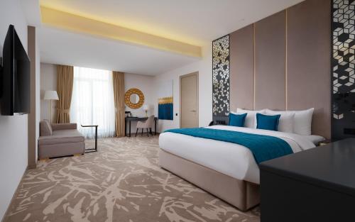a hotel room with a large bed and a living room at Mercure Tashkent in Tashkent