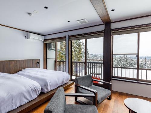 a bedroom with a bed and a balcony with windows at kamosu mori in Tokamachi