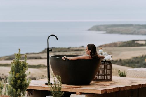 a woman sitting in a black bath tub on a deck at Wander on Kangaroo Island in Stokes Bay