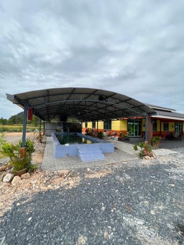 ein Gebäude mit einem großen Dach und einem Pool in der Unterkunft OLAH HOMESTAY in Kodiang