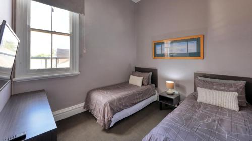 sypialnia z łóżkiem i oknem oraz łóżko sidx sidx sidx w obiekcie Commercial Hotel Lockhart w mieście Lockhart