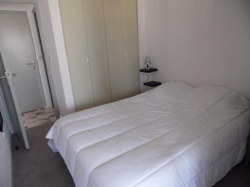 - un lit blanc dans une chambre blanche avec une porte dans l'établissement Appartement 3 pièces rénové, proche plage et commerces, pour 4 personnes - FR-1-326-669, à Marseillan