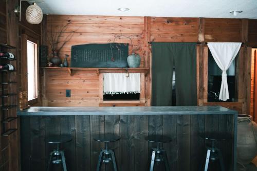 a bar in a cabin with three stools at Sugi Chalet in Myoko