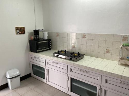 a kitchen counter with a stove and a microwave at Chez Bibi in Maison Blanche