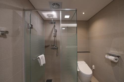 a bathroom with a toilet and a glass shower stall at Hotel Susung Spa Resort in Daegu