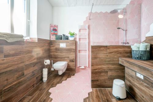 ein rosafarbenes Bad mit einem WC und einer Dusche in der Unterkunft Gustava 28 in Graal-Müritz