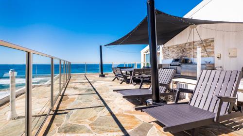 a patio with chairs and an umbrella on the beach at Viscount on the Beach in Gold Coast