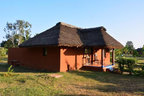 a small hut with a thatched roof in a field at Red Earth Kabini in Begūr