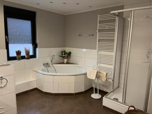 ein weißes Bad mit einer Badewanne und einer Dusche in der Unterkunft Ferienwohnung im Harz Wohlfühltempel in Winzenburg