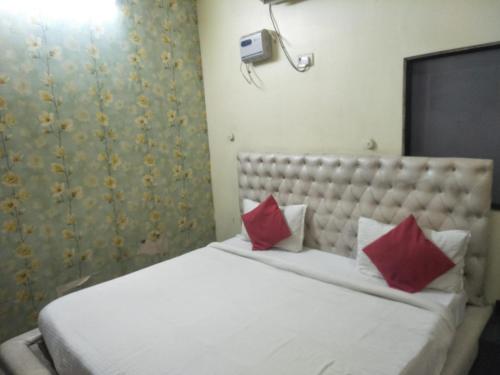 ein Schlafzimmer mit einem großen weißen Bett mit roten Kissen in der Unterkunft Hotel Shiv Mahima Inn By WB Inn in Allahabad