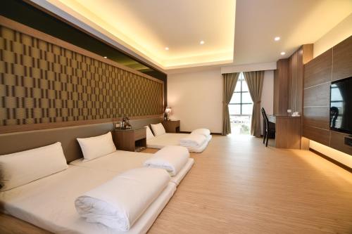 a hotel room with white beds and a television at Chuan Cheng Castle in Magong