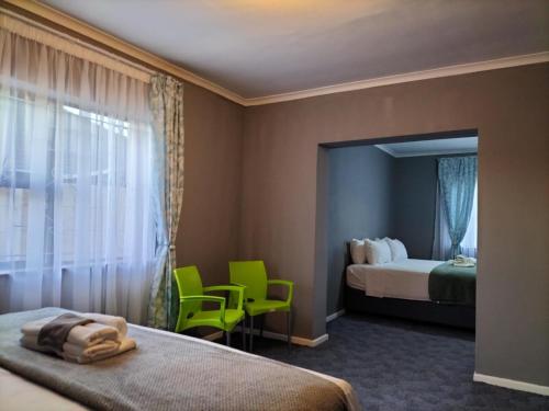Habitación de hotel con 2 camas y 2 sillas verdes en Step-by-Step Self-Catering and B&B, en Bellville