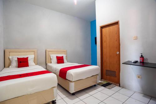 a bedroom with two beds and a desk at RedDoorz near Margonda Raya in Kemirimuka Dua