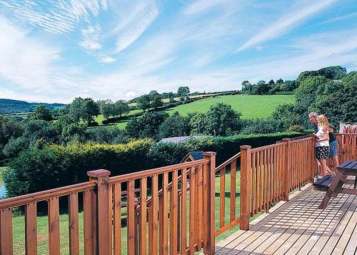 two people standing on a wooden deck with a fence at Avalon Cottages in Llangynin