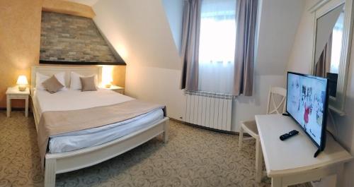 1 dormitorio con 1 cama y escritorio con TV en Hotel Bucegi, en Sinaia