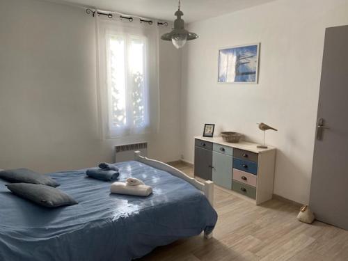 una camera con letto blu, cassettiera e finestra di La Cebette a Saint-Cyr-sur-Mer
