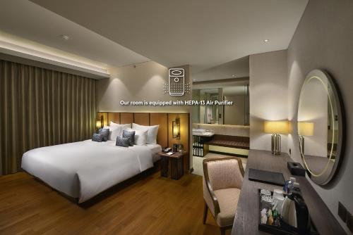 um quarto de hotel com uma cama e um espelho em Golden Tulip Holland Resort Batu em Batu