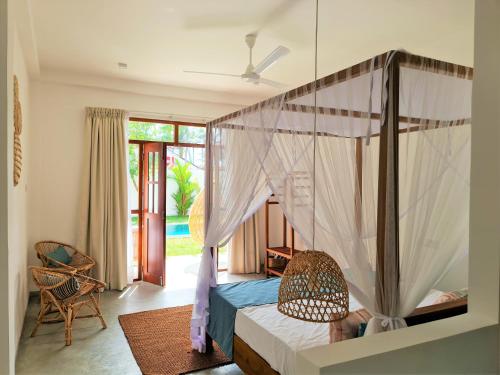 a bedroom with a canopy bed and a chair at Ohana Surf Guest House in Ahangama