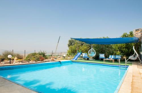 una piscina con columpio y sombrilla en Galilaeaen Loft en Chorazim