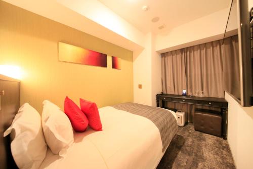 a hotel room with a bed with red pillows at Centurion Hotel Ikebukuro Station in Tokyo