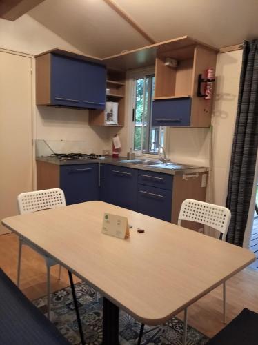 a kitchen with a table and chairs and blue cabinets at Villaggio Turistico Il Lago Dorato in Carlazzo