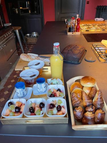 una mesa con bandejas de comida y una botella de zumo de naranja en Château de Beauchamp- La chapelle de Guinchay, en La Chapelle-de-Guinchay
