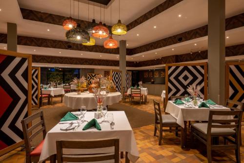 una sala da pranzo con tavoli e sedie bianchi di Mantis Akagera Game Lodge a Akagera