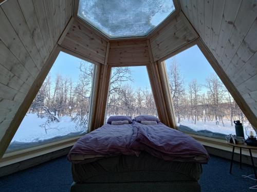 a bedroom with a bed in a room with windows at Aurora Cone in Kiruna