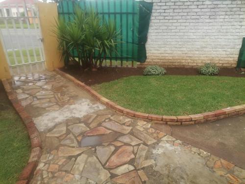 a backyard with a stone walkway and a yard withgrass at New Dawn Guest House in Brakpan